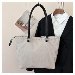 Detail of light beige nylon tote bag with black straps and adjustable drawstring side