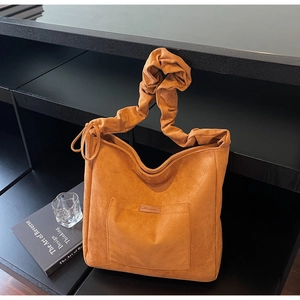Detail of orange suede tote bag with wide ruched strap and side drawstring texture