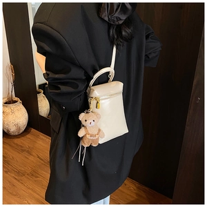 Mini sac bandoulière en cuir PU crème avec pendentif ours en peluche sur fond bois sombre