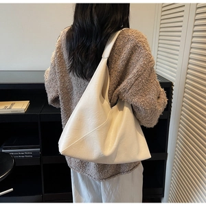 Model wearing a large white faux leather tote bag with pleated texture for autumn fashion