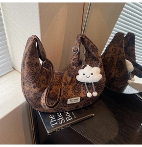 Detailansicht der braunen Retro-Tasche mit Paisley-Muster und flauschigem Wolkenanhänger