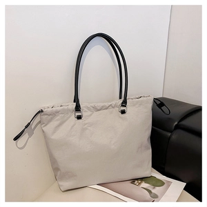 Detail of minimalist beige tote bag featuring black drawstring and premium shoulder straps