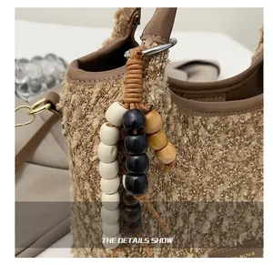 Dettaglio del ciondolo di perle multicolore con nodo intrecciato su borsa in tweed