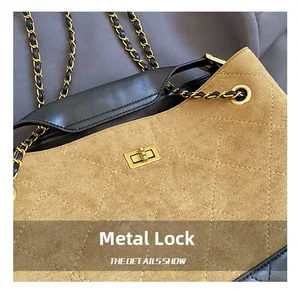 Detalle del cierre de metal dorado y textura de ante acolchado en el bolso de cadena