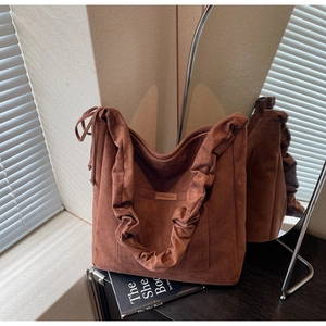 Close-up of coffee brown suede tote bag featuring pleated straps and side drawstrings