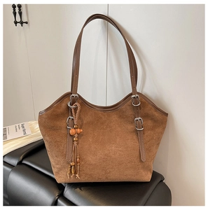 Detail of matte brown tote bag showing suede texture and ethnic tassel charm