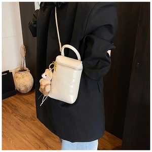 Détail d'un mini sac bandoulière blanc crème avec un joli pendentif ours en peluche marron