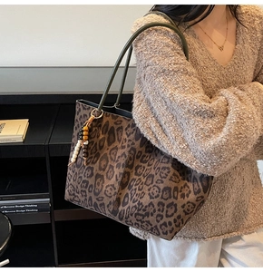 Détail du cabas en daim léopard avec perles colorées sur un pull en maille beige