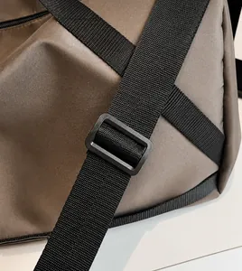 Détail de la bandoulière réglable en nylon noir sur le sac de voyage marron foncé