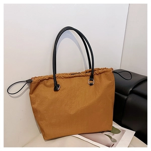 Detail of caramel tote bag showing crinkled nylon fabric and drawstring closure