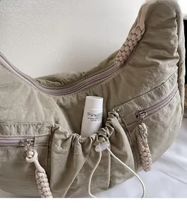 Detail view of the gray-green nylon bag featuring a front drawstring pocket for storage