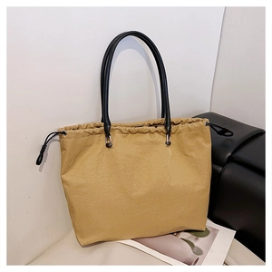 Detail of khaki tote bag with unique pleated texture and thin black handles for daily use