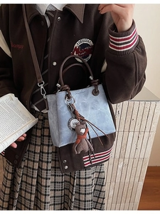 Mini borsa a secchiello azzurra con manico a cerchio marrone e ciondolo a orsetto su modella