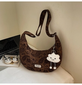 Detail der braunen Vintage-Paisley-Tasche mit weißem Wolken-Plüschanhänger und Logo