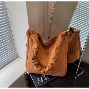 Detail of a brown suede tote bag featuring unique scrunchie straps and a side pocket