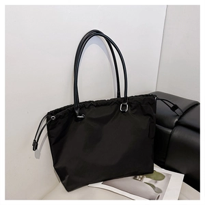 Close-up of black nylon tote bag featuring leather straps and drawstring closure detail