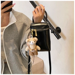 Détail du mini sac boîte en cuir verni noir avec un charmant ours en peluche et zip doré