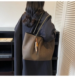 Détail d'un grand sac cabas en daim vert olive avec breloque en perles sur modèle