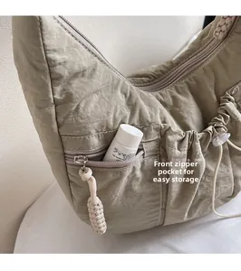 Detail of light green pleated nylon crossbody bag showing the front zipper pocket and texture