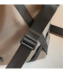 Detail eines verstellbaren schwarzen Nylon-Schultergurts mit Schnalle an brauner Reisetasche