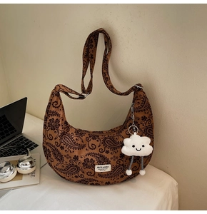 Makroaufnahme einer Retro-Paisley-Halbmondtasche in Braun mit weißem Wolkenanhänger