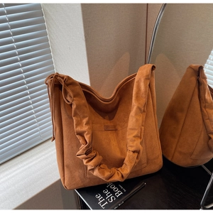 Detail of orange-brown hobo bag showing soft suede texture and drawstring side design