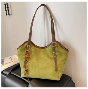 Detail of green faux suede tote bag with brown leather handles and bead charm
