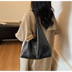 Modern black hobo tote bag shown from the back on a model wearing a trench coat