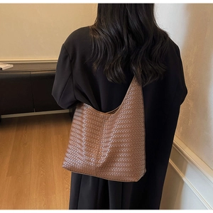 Vue arrière du sac Hobo marron tressé porté sur un modèle avec manteau