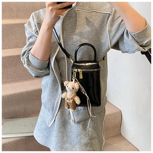 Détail du mini sac en cuir verni noir avec zip doré et breloque ours en peluche