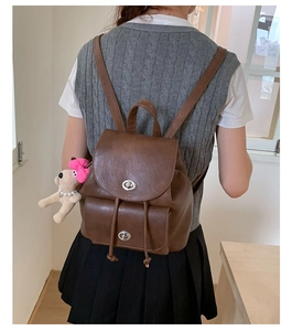 Detail of vintage brown PU leather backpack with silver twist lock and cute dog pendant