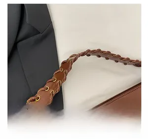 Détail d'une poignée en cuir tissé à la main avec œillets sur un sac marron