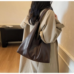 Detail of dark brown tote bag in vintage PU leather worn by a model in a modern interior