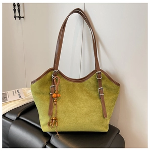 Detail of green suede tote bag with brown leather handles and wooden bead tassel