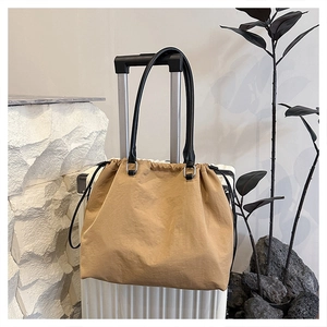 Detail of khaki drawstring tote bag on suitcase showing nylon texture and shoulder straps