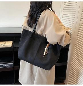 Grand sac cabas chic en daim noir avec détails en perles de bois porté par un mannequin