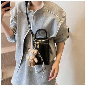 Détails d'un mini sac noir brillant avec pendentif ours et fermeture éclair dorée