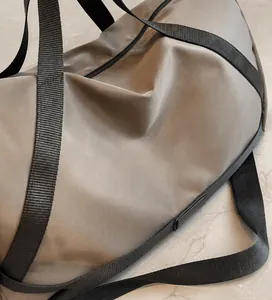Détail d'un sac de voyage spacieux en tissu brillant avec des poignées en nylon noir