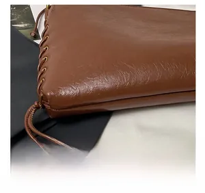 Détail macro d'un sac en cuir marron avec tressage latéral et texture de couture précise