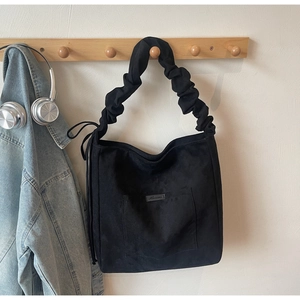 Detail of black tote bag with textured fabric and unique ruched cloud shoulder strap