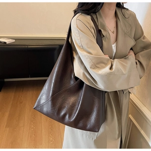 Detail of soft leather texture and diagonal stitching on dark brown tote bag