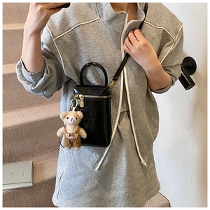 Détail d'un mini sac bandoulière noir avec un pendentif ours et des finitions dorées