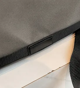 Détail de la couture de la bandoulière et garniture en cuir sur le sac de voyage gris