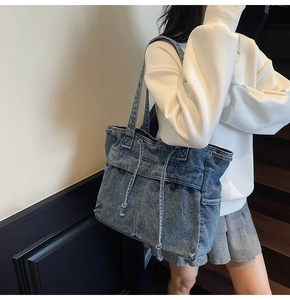 Denim tote bag with drawstring pocket shown on shoulder with vintage wash texture