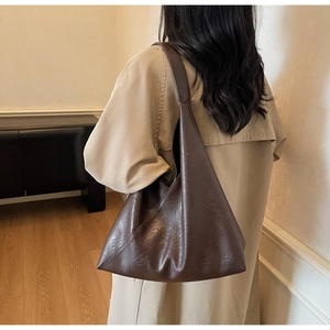 Detailed view of dark brown tote bag with natural pleated texture and wide shoulder strap