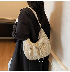 Detailed back view of a beige pleated crescent crossbody bag with woven zipper pull details