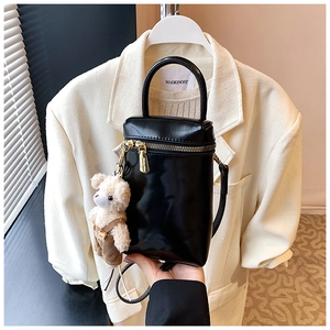 Détail d'un mini sac noir avec fermetures dorées et pendentif en peluche d'ours mignon