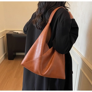 Close-up of brown faux leather tote bag showing diagonal stitching and soft matte texture