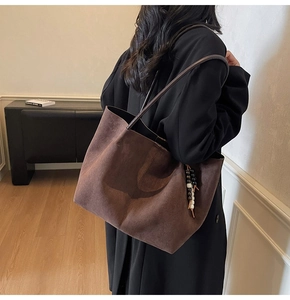 Détail du sac cabas en daim marron foncé avec pendentif en perles et texture raffinée