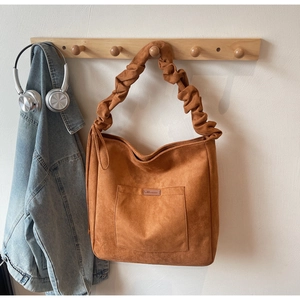 Brown suede tote bag detail featuring pleated shoulder strap and front patch pocket